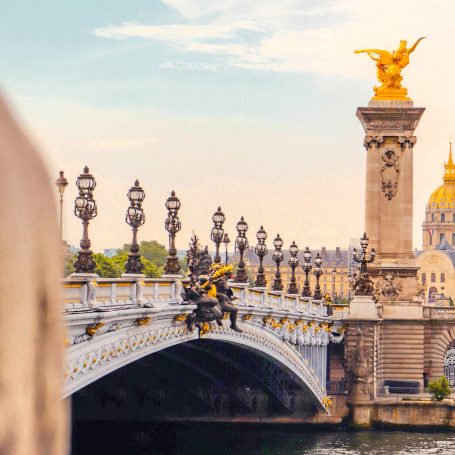Pont Alexandre III avec des sculptures dorées et un ciel bleu clair.