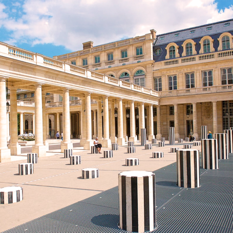 Colonnes de Palais Royal à Paris, avec un ciel partiellement nuageux.