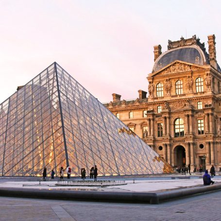 Pyramide en verre du Louvre, bâtiment historique en arrière-plan.
