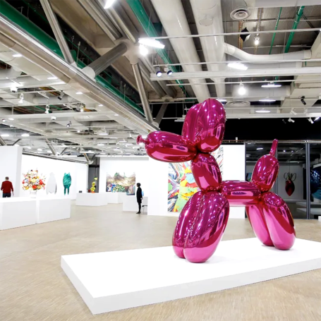 Un grand chien en ballon rose vif dans une galerie d'art moderne.