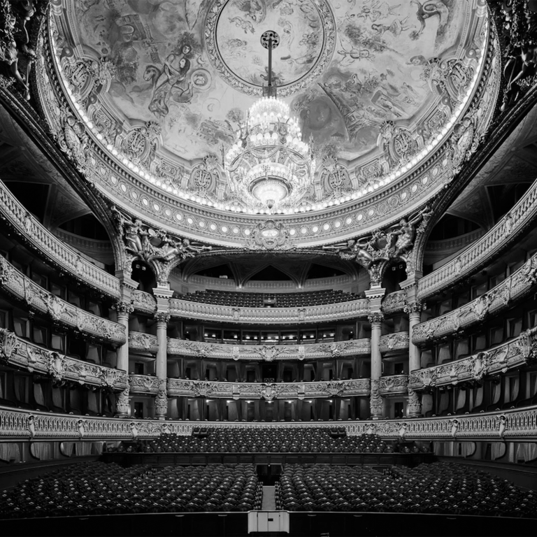 Salle de théâtre opulente avec un plafond décoré et des sièges en rangées.