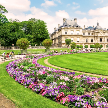 Jardin bien entretenu avec des fleurs colorées et un élégant château en arrière-plan.