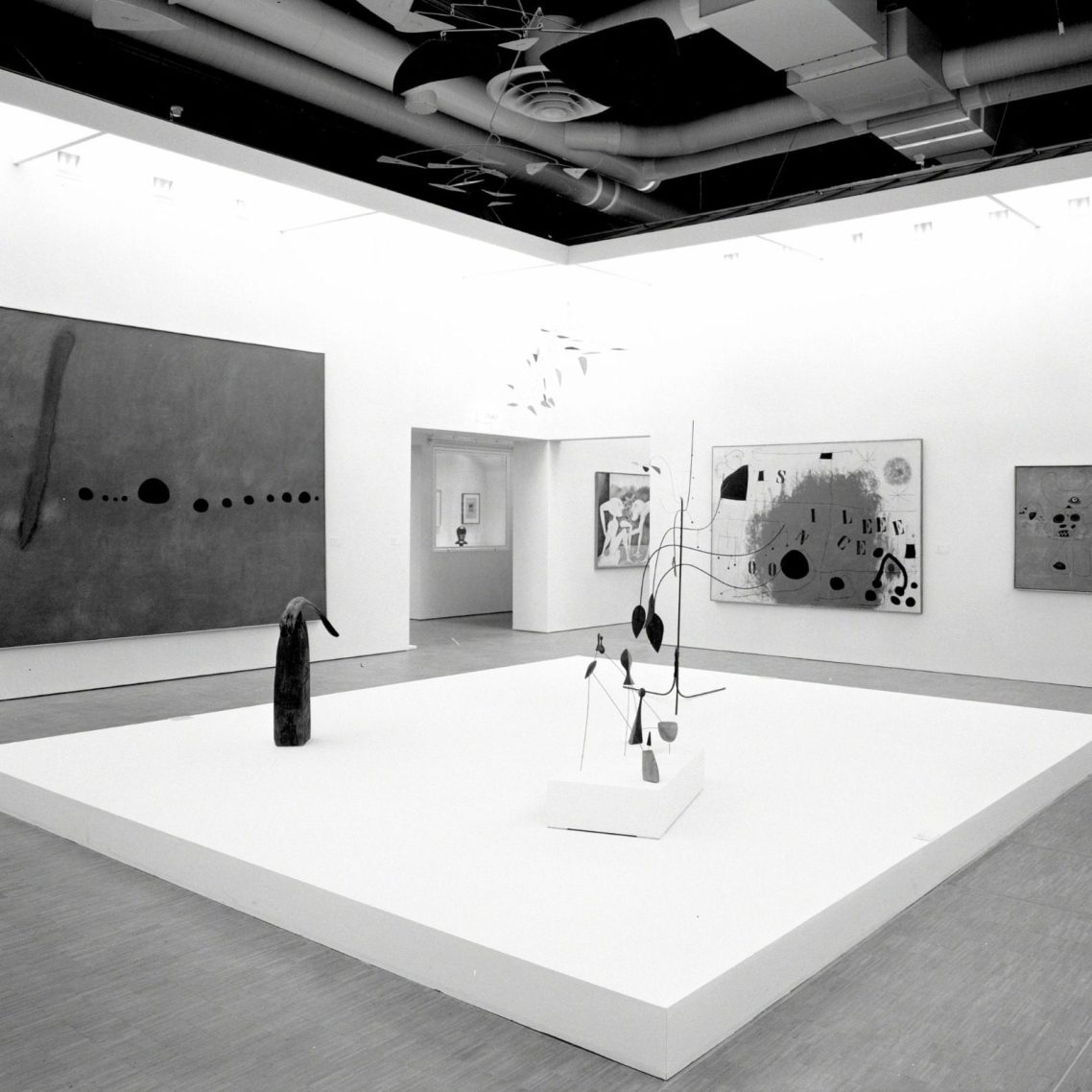 Salle d'exposition d'art moderne avec sculptures et tableaux sur des murs clairs.