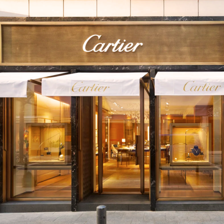 Façade d'une boutique Cartier avec des rideaux en tissu portant le logo.