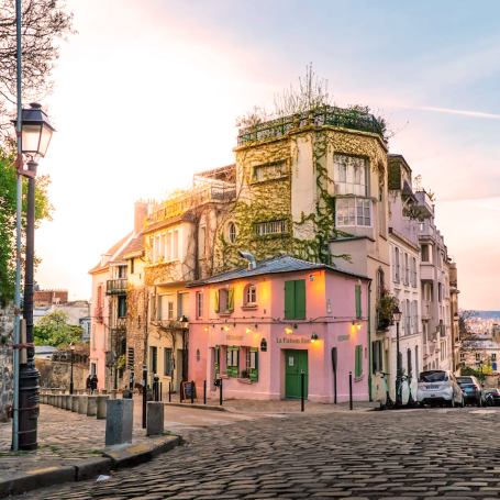 Maison colorée à l'angle d'une rue pavée, éclairée par un coucher de soleil.