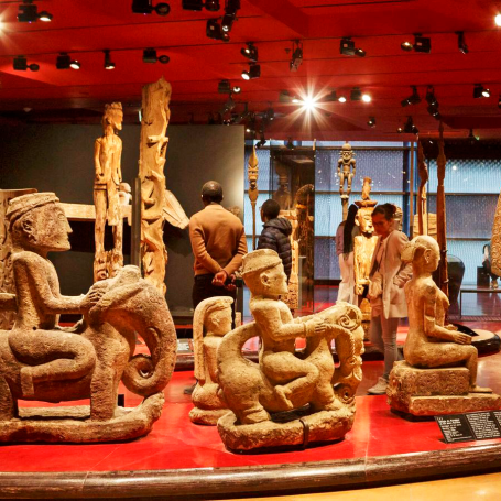 Sculptures et statues anciennes exposées dans un musée, avec des visiteurs en arrière-plan.