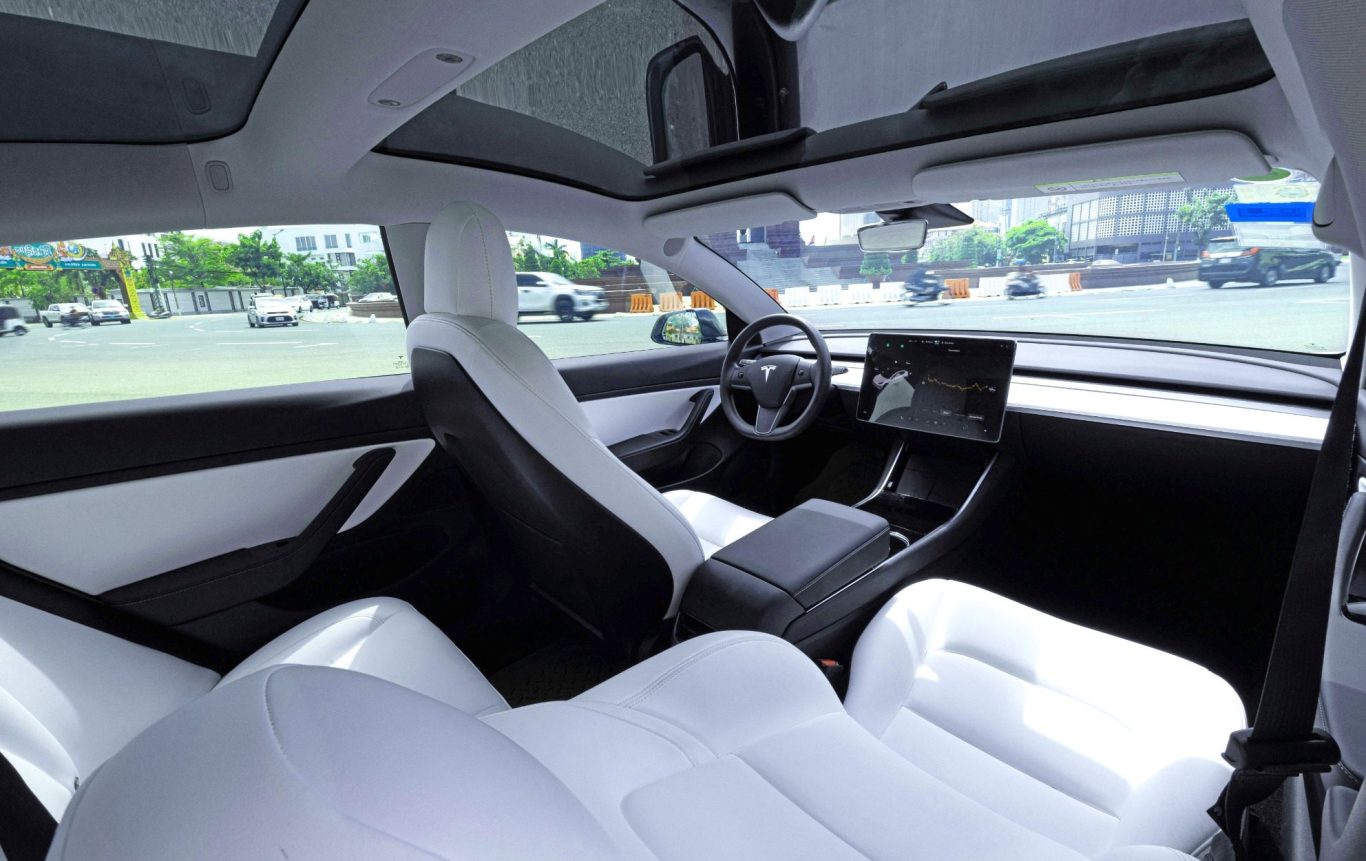 Intérieur d'une voiture moderne avec sièges blancs et tableau de bord minimaliste.